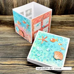 Weiße Geschenkbox mit Fischen, Muschel und geprägten Blasen auf Seitenwänden und Deckel