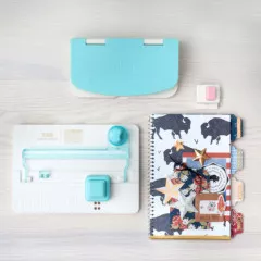 Flatlay mit Tab Punch Board, Schablone, farbigen Papieren und Planer auf Holzboden